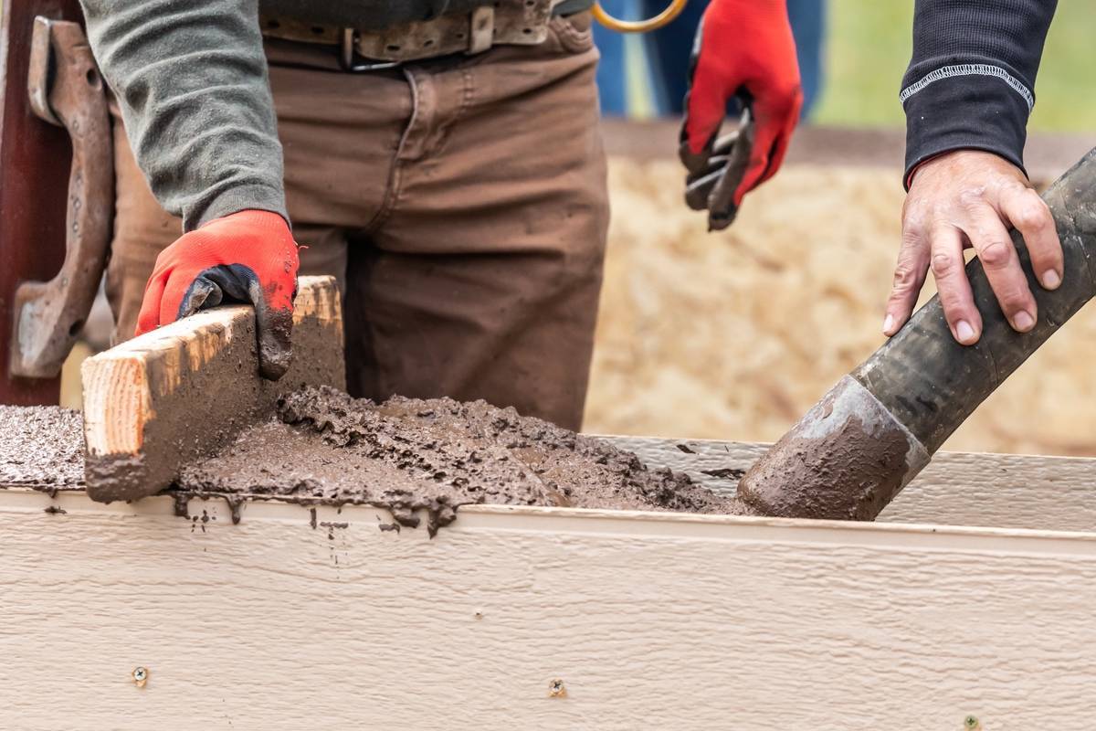 Concrete Contractors Tulsa OK 34082126 Construction Worker Leveling Wet Cement Into Wood Framing