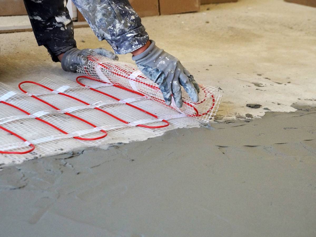 Concrete Contractor Tulsa, Oklahoma 47744882 A Worker Unfolds A Roll Of Warm Electric Floor For Laying Under A Cement Screed