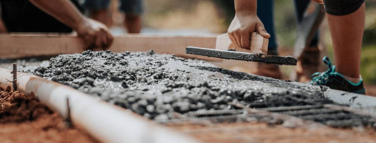 Construction Worker Leveling Wet Cement Into Wood Framing