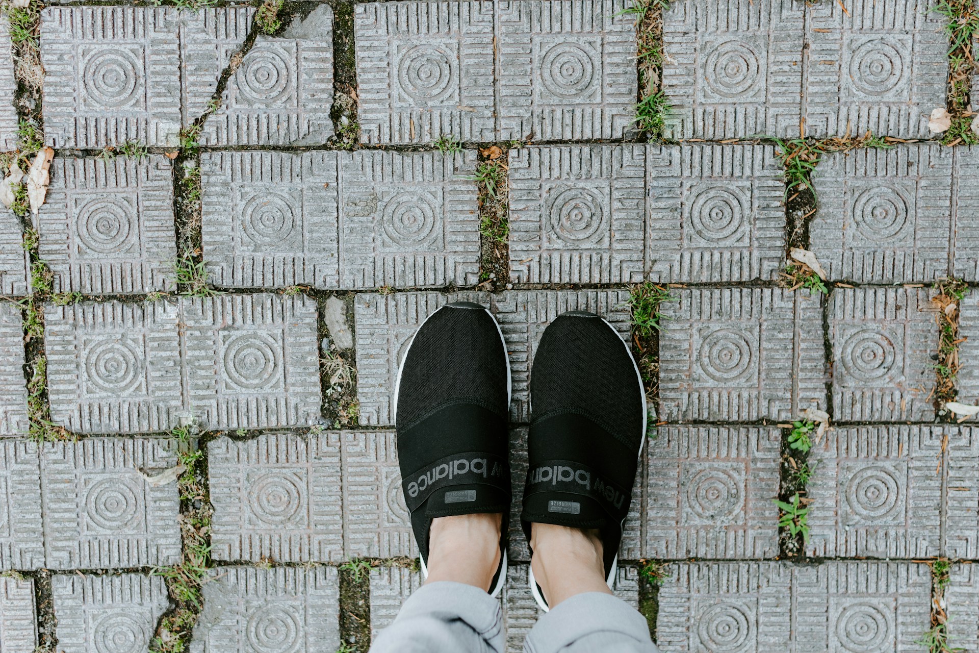 A person's feet standing on a brick walkway.