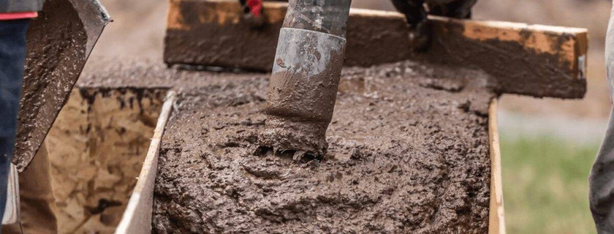 Construction Worker Leveling Wet Cement Into Wood Framing